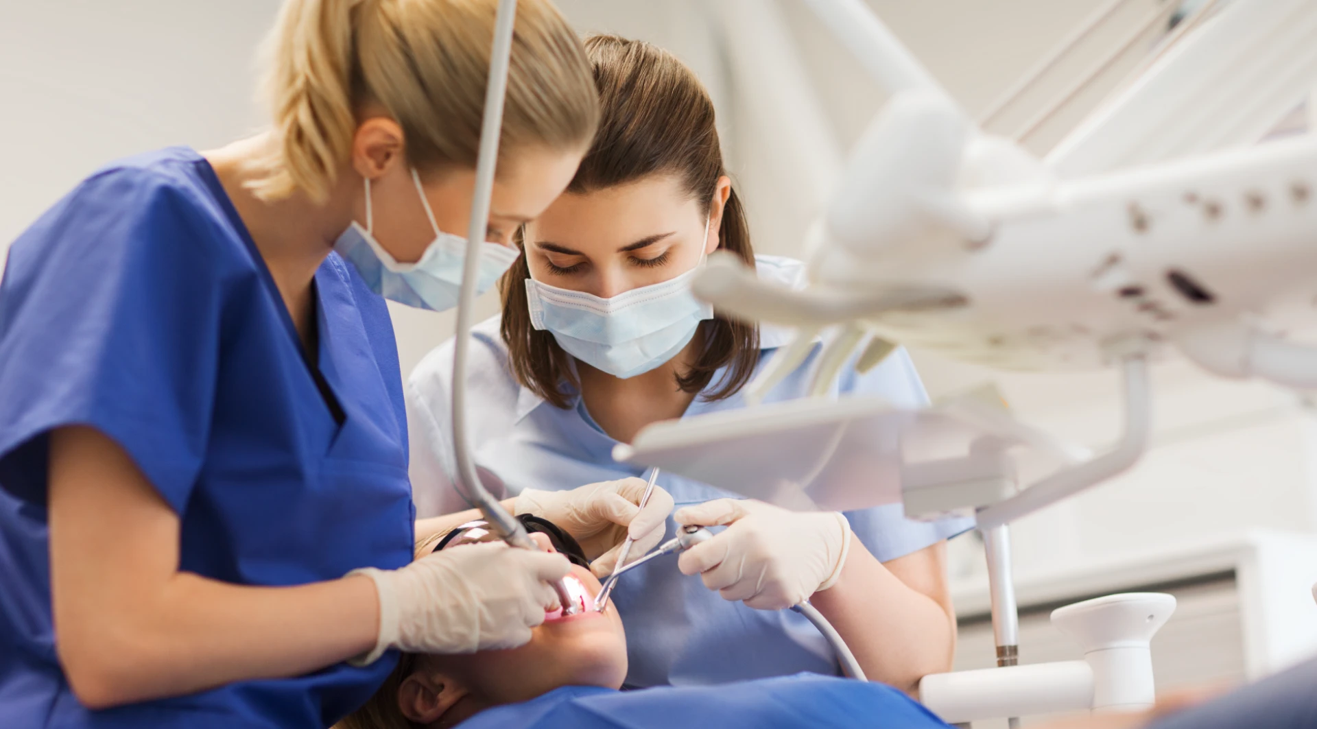 Echipă de medici stomatologi profesioniști efectuând tratament dentar cu instrumentar modern în clinică